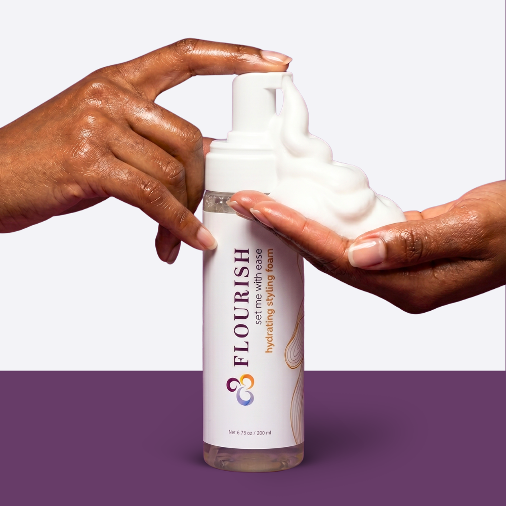 Styling foam bottle being pumped into brown hands against a purple background
