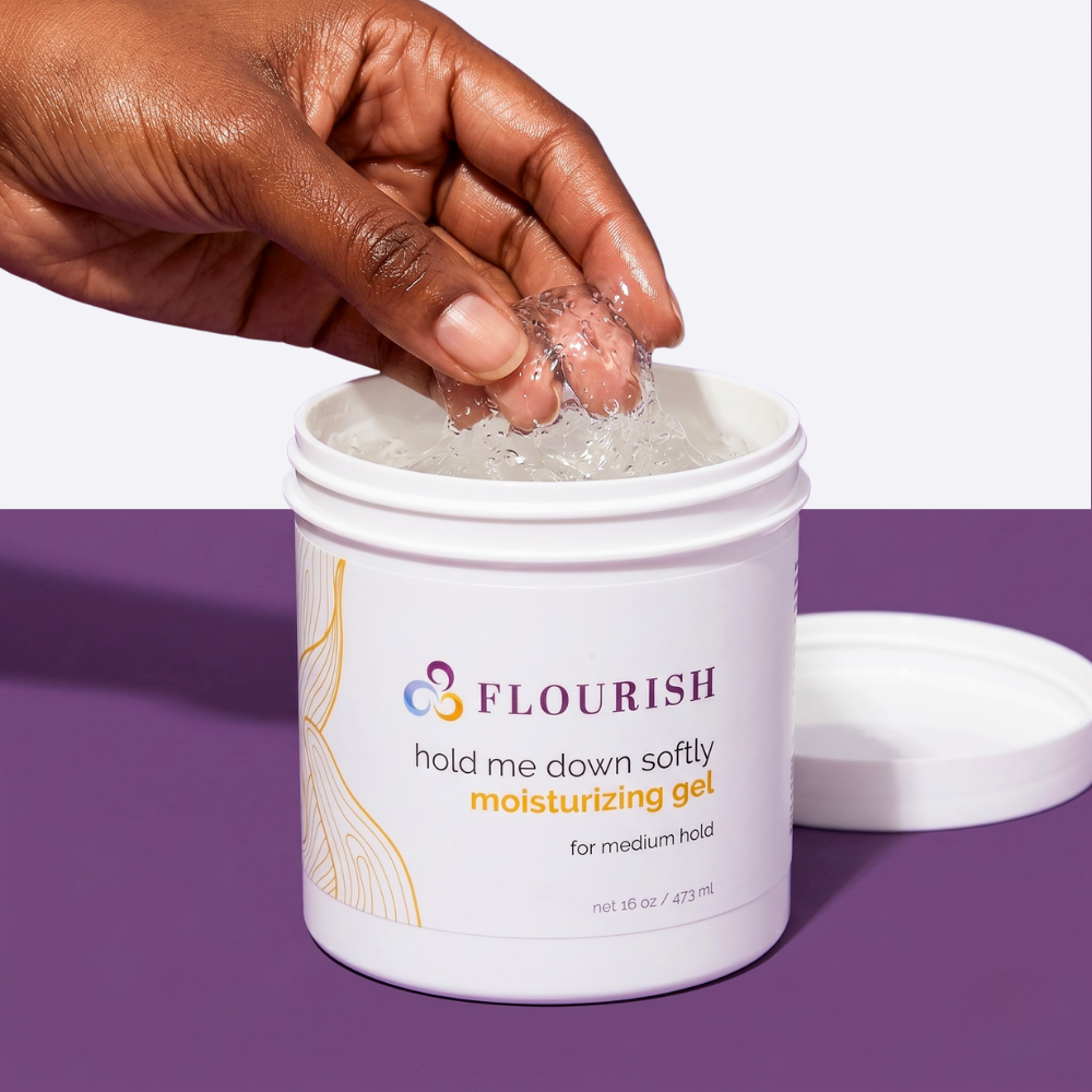 Hand scooping moisturizing hair gel from a container on a purple background