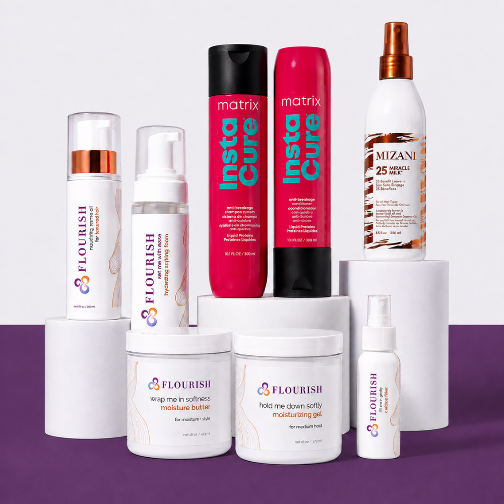 A collection of hair care products from Flourish, Matrix Instacure, and Mizani arranged on white display pedestals against a split white and purple background. The products include a black hairbrush, and several white jars and bottles.