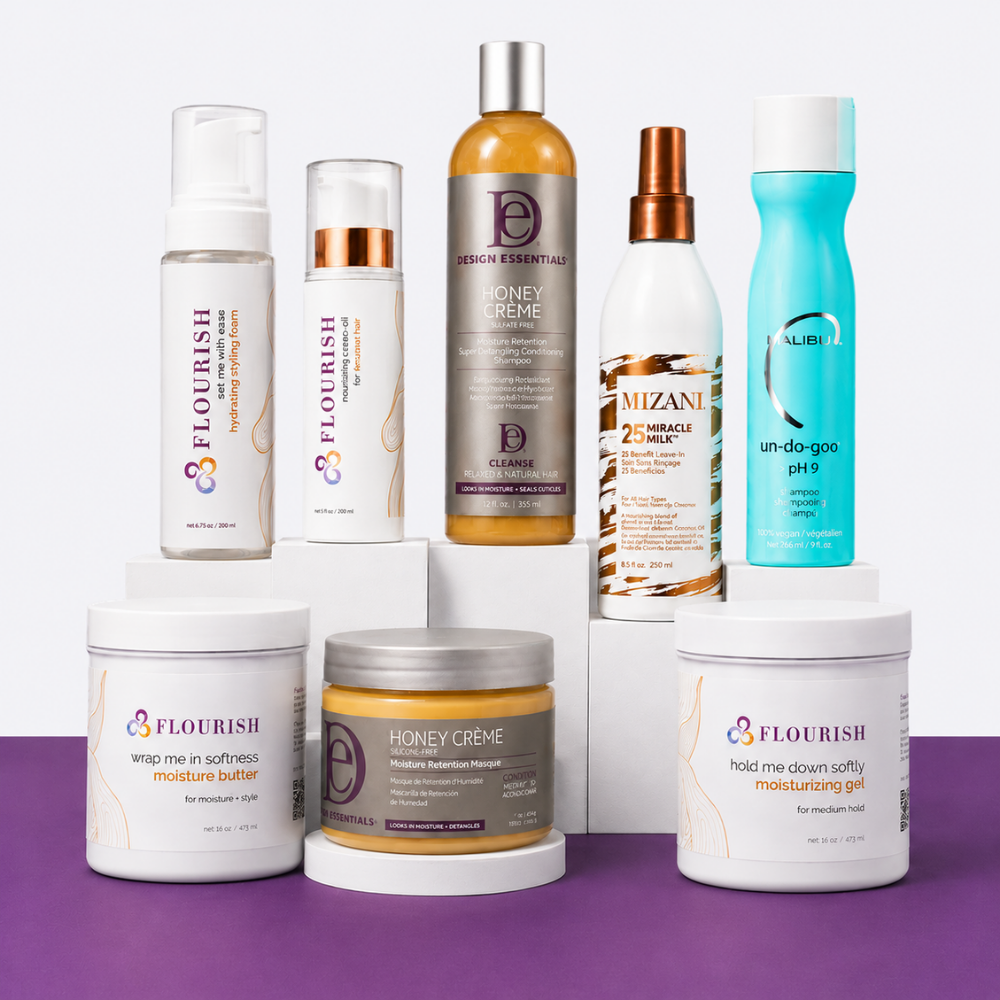 A collection of haircare products from Flourish and Mizani arranged on white display blocks against a split white and purple background. The products include a honey creme treatment, a miraculous hair repair mask, an un-do-goo pH 9 conditioner, a softness moisturizing gel, a wrapping moisturizing butter, a softening spray, and a black hairbrush.